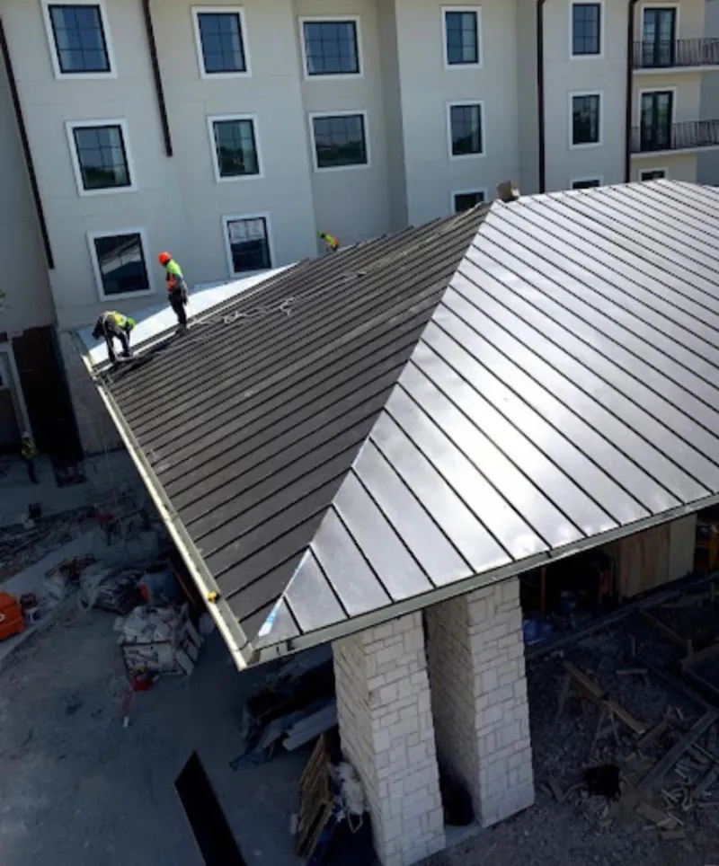 Crew installing standing seam metal roof panels on a commercial project in Sachse